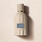 Beige perfume bottle with a blue label on a beige background